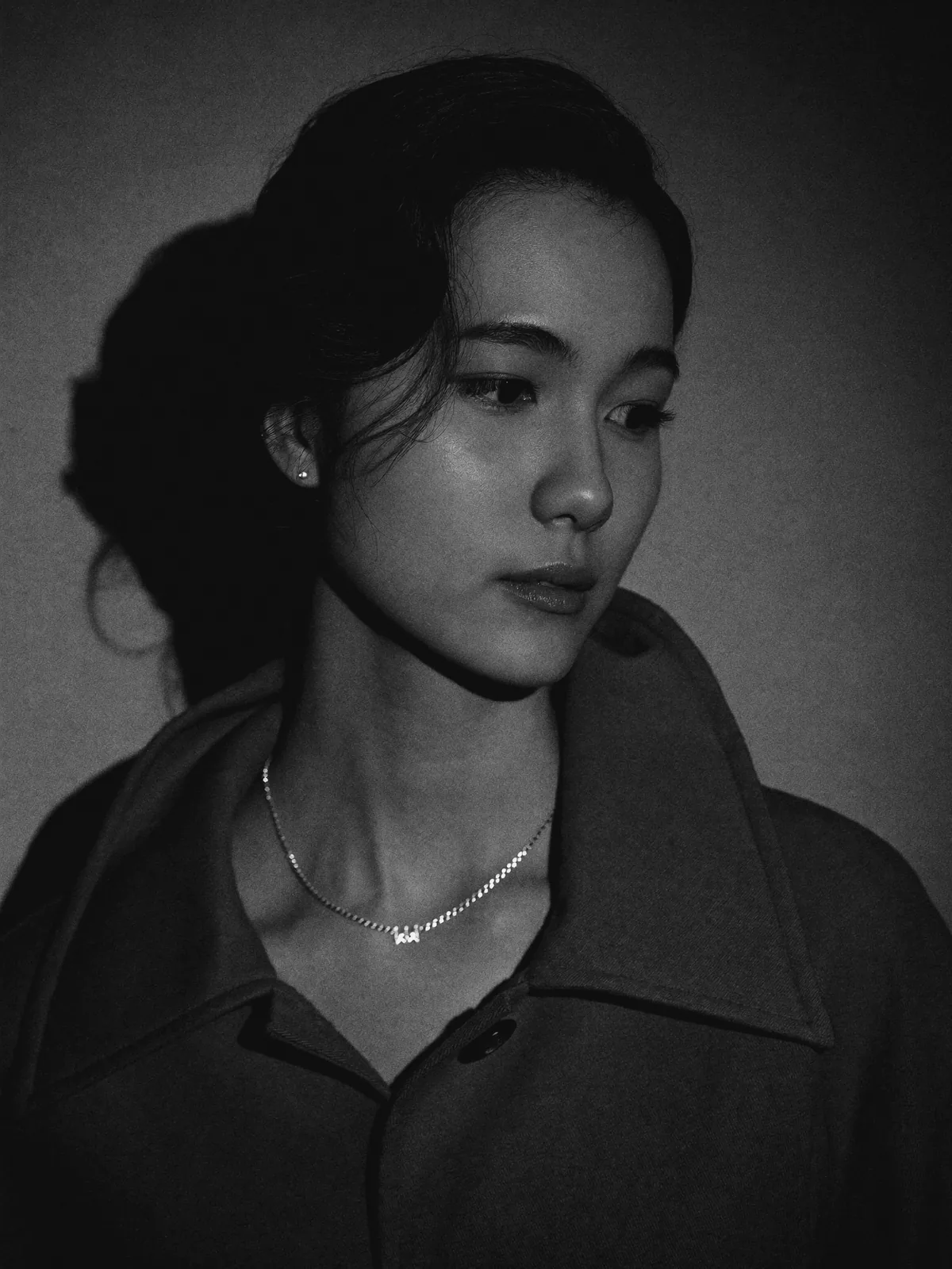 Side-lit portrait, collar up, silver station necklace