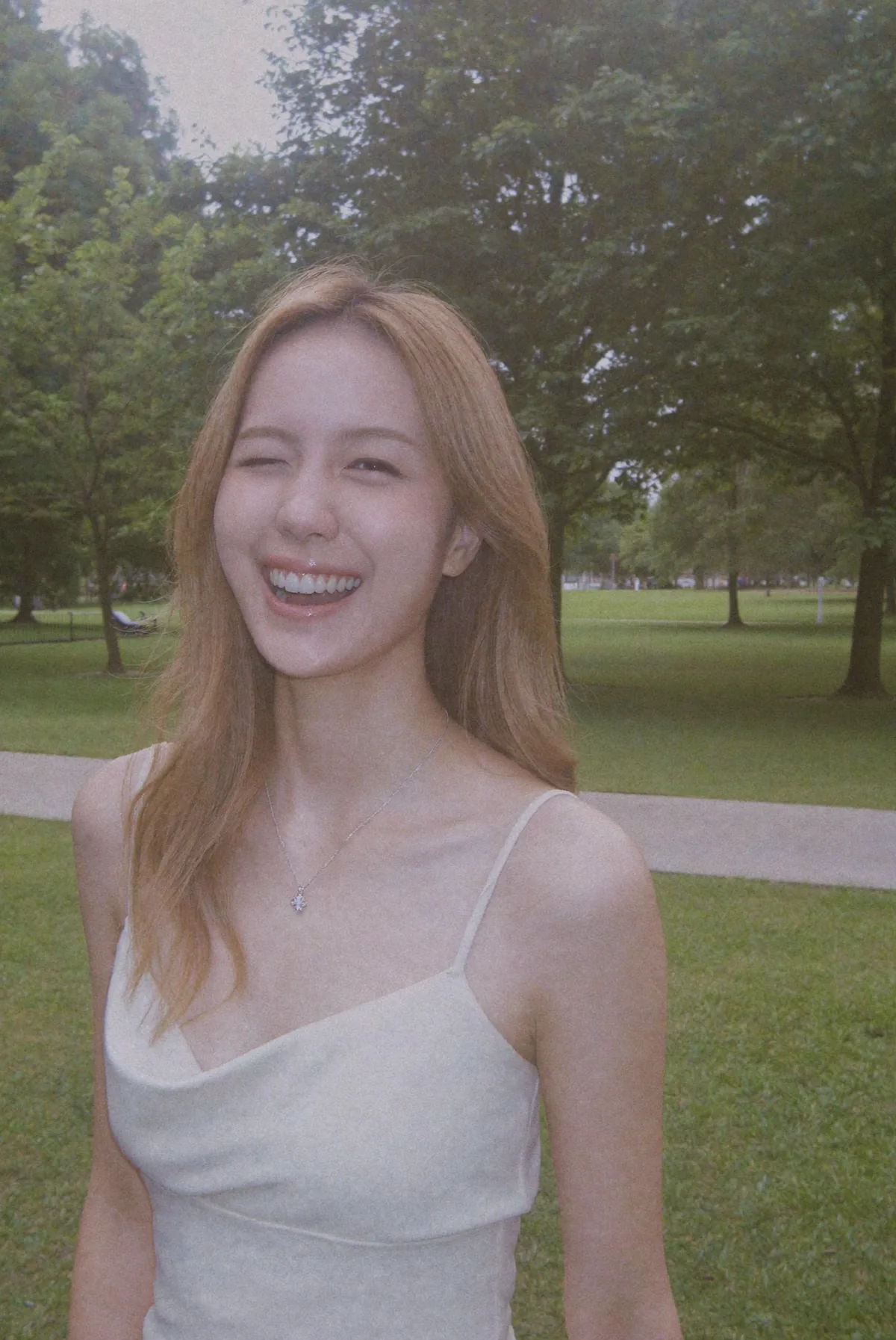 Laughing in a park, a silver pendant